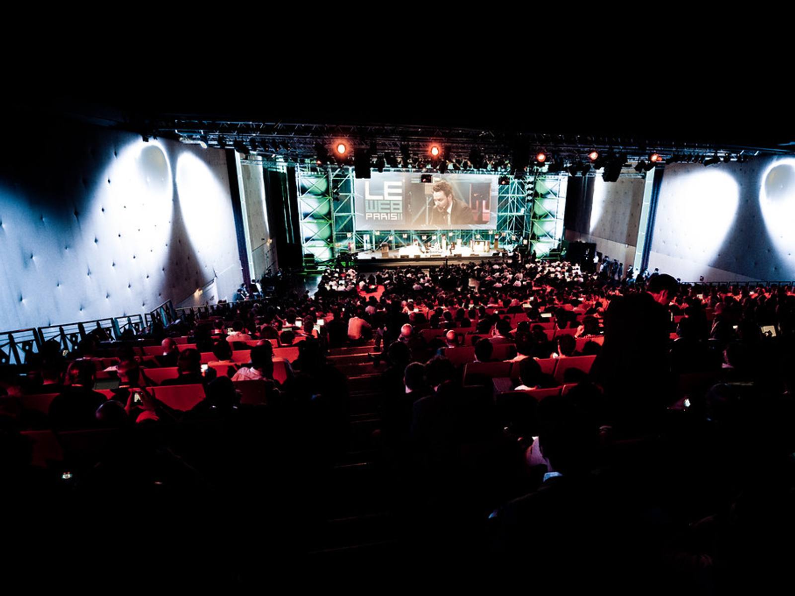 An audience seated in a lecture hall, facing a stage and screen, representing accessible in-person events.