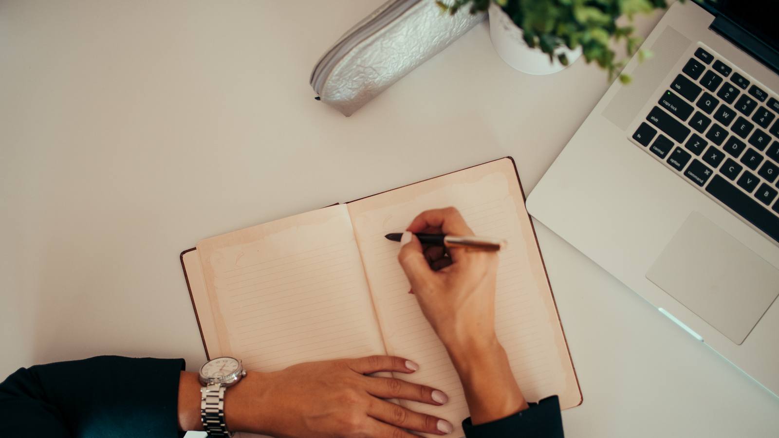 An open notebook beside a laptop on a desk, representing journal entries yet to come.